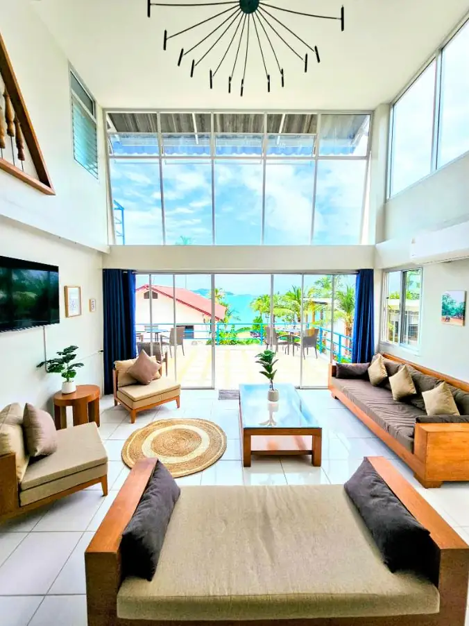 Double-height Penthouse living room with floor-to-ceiling windows onto a sea-view terrace